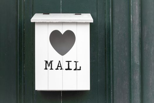 White vintage wooden mailbox with empty heart. In front of the written mail.
