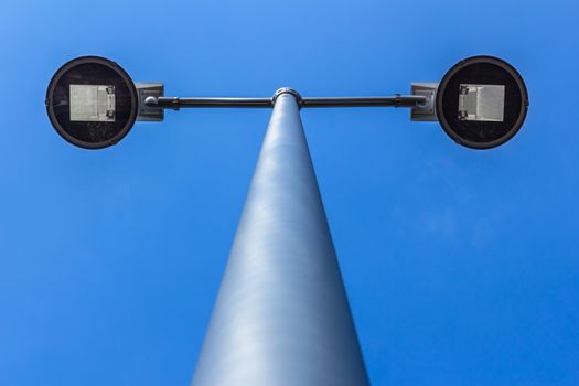 Modern electric street light pole over blue sky with clouds. Bottom view.