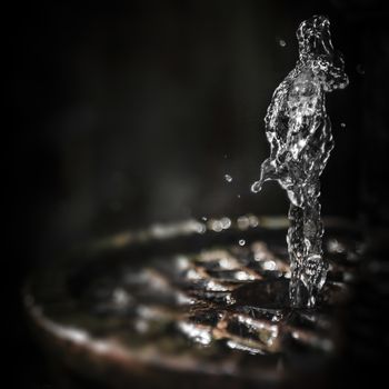 Human figure dancing in splash of water in the fountain on abstract background