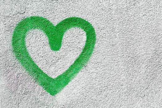 Green heart shaped on wall background. Symbol of love on rustic wall. It can be used as a Valentine's theme, poster, wallpaper, design t-shirts and more.