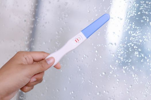 Closeup woman hand holding pregnancy test with happy moment, health care concept, selective focus
