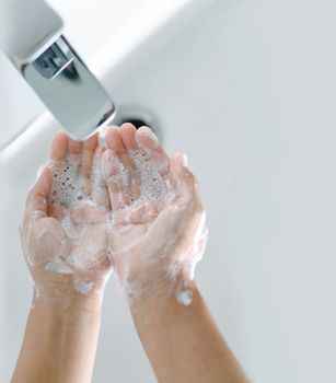 Closeup woman's hand washing with soap in bathroom, selective focus