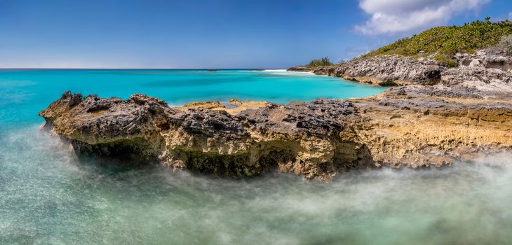 Beautiful panoramic view of a cliff in tropics. Turquoise water. Blue sky as a background. Long exposure.