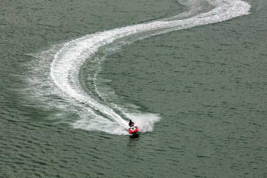 Red jetski moving very fast leaving white trace behind it. Sports, competition concept. Aerial view.