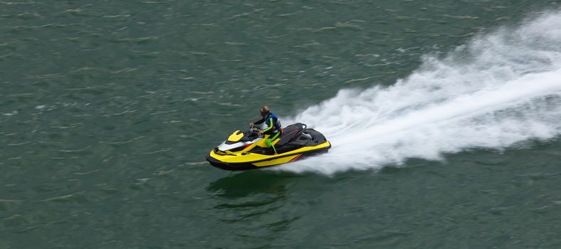 Yellow jetski moving very fast leaving white trace behind it. Close shot. Sports, competition concept. Aerial view.