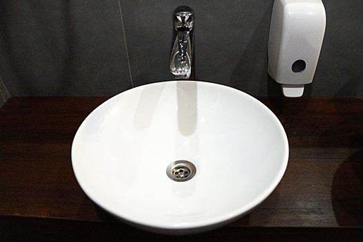 round white sink and soap dispenser, bathroom interior.