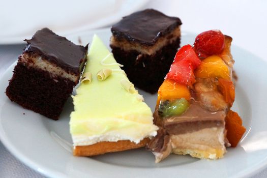 pieces of different cakes on a white dish, sweet dessert