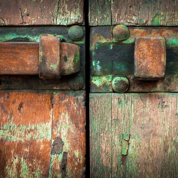 Old gate locked with a rusty iron latch