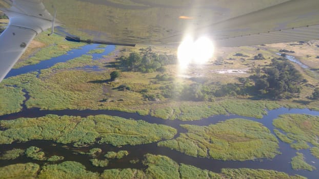 Aerial view at Moremi national park in Botswana, Africa, as seen from a small aircraft. Wing visible, bright sunshine on blue sky. Travel and Tourism