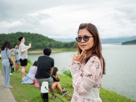 Phetchaburi, Thailand - 16 August 2020 Editorial illustrations.
Thai women stand to take pictures at the dam ridge With a lot of people visiting this place.