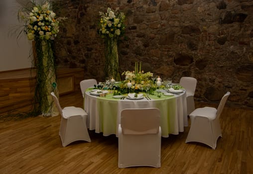 Decorated table with table compositions and burning candles, green, white