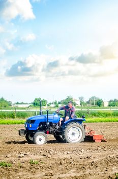 The farmer drives a tractor with a milling unit equipment. Loosening land cultivation Use of agricultural machinery to speed up work. Farming. Plowing field. The stage of preparing soil for planting.