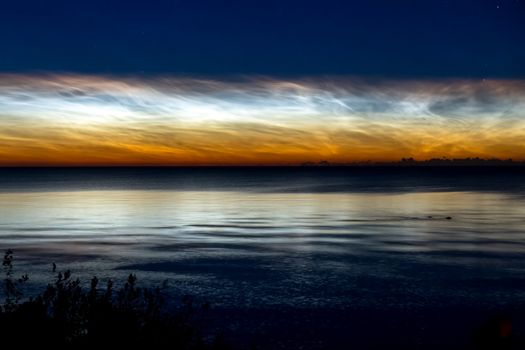 Dawn on the lake. Feathered clouds glow at dawn.