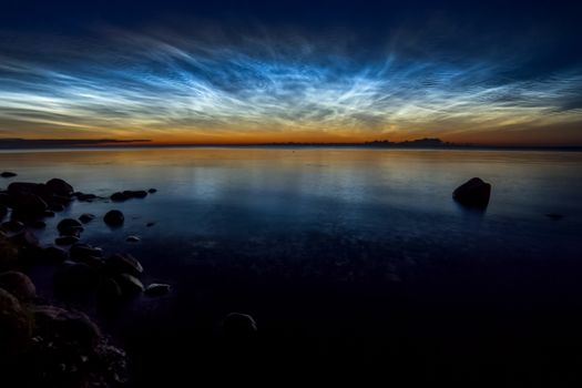 Dawn on the lake. Feathered clouds glow at dawn.