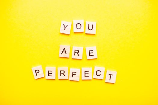The inscription you are perfect made of wooden blocks on a light yellow background.