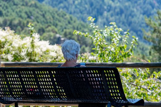 Escaldes Engodany, Andorra : 20 August 2020 : Old woman whit telephone in the Engolasters lake in Escaldes Engordany, Andorra in summer 2020