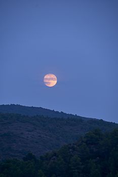 The moon rising between the mountains, full moon, blue tones, mountain, alpine landscape