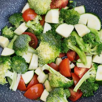 Green vegetables, broccoli, zucchini, tomatoes in a WOC pan
