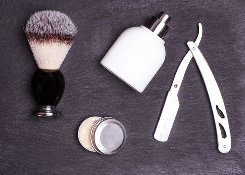 Razor, brush, perfume and balsam on a black background.