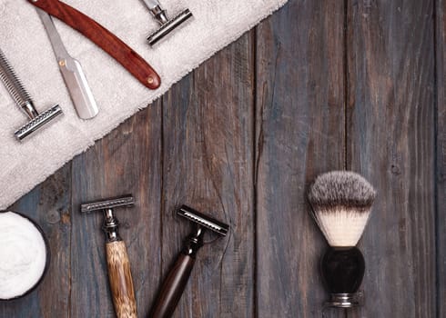 Razors, brush, towels and foam on a wood background.