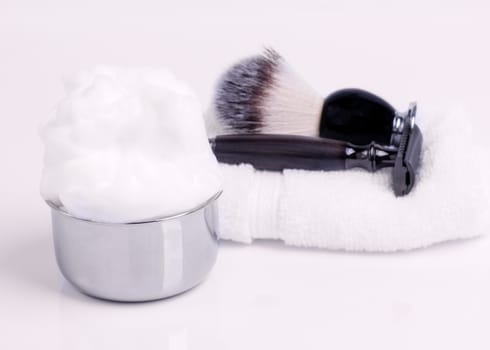 Razor, brush, towels and foam on white background.