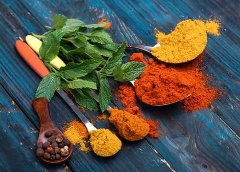 Colorful spices and wooden spoon on black background