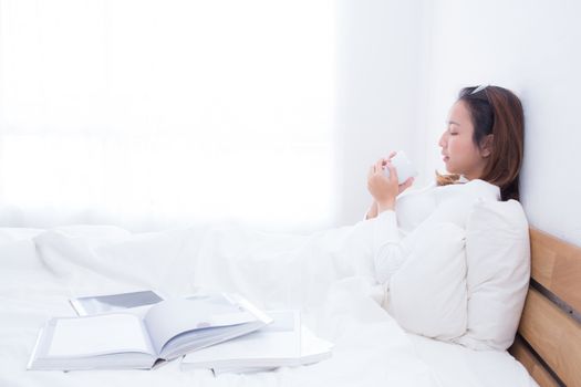 Asian woman with cup of coffee in bedroom with morning.