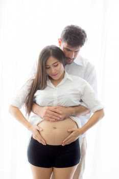 Pregnant Mother and father standing hugging holding belly, family concept.
