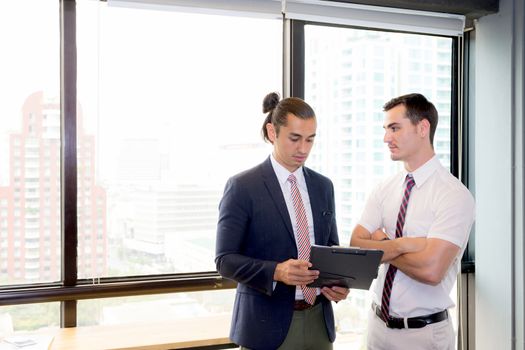Asian young businessman two people holding clipboard and discussing work in the meeting room, business concept.