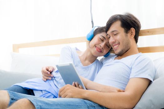 Beautiful asian young couple listening to music with tablet on bed, Love, dating,Young couple in sitting together in bed using a Tablet.