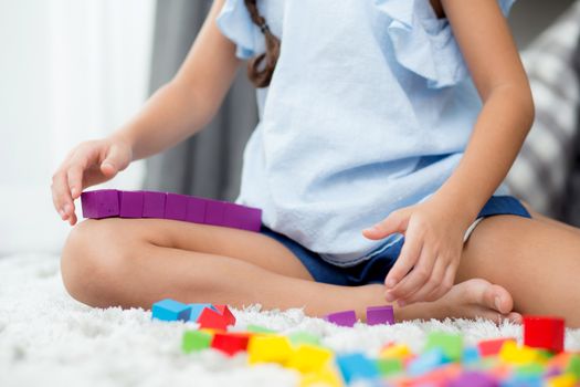 Close up of hand child playing with colorful plastic block at floor. Early learning developing to children with toys.