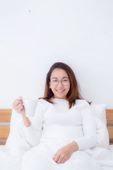 Asian woman with cup of coffee in bedroom with morning.