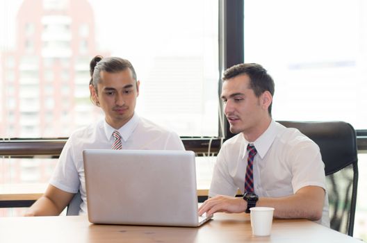 American people business two young caucasian modern man sitting in a meeting room using and looking laptop together.