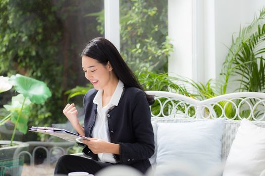 Asian business woman holding clipboard folder and gesture glad in the office.
