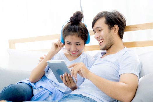 Beautiful asian young couple listening to music with tablet on bed, Love, dating,Young couple in sitting together in bed using a Tablet.