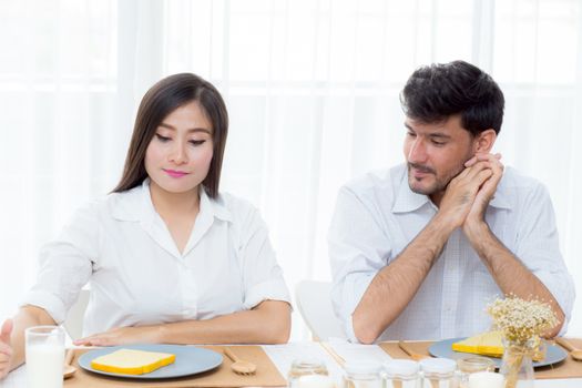 Cheerful asian young man and woman having sitting lunch and talking  together at kitchen