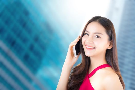 Young beautiful asian woman wear red dress talking on smart phone with happy and success on city background - communication business concept.