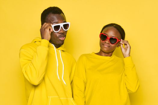 Man and woman african appearance yellow isolated background communication friendship dating sunglasses