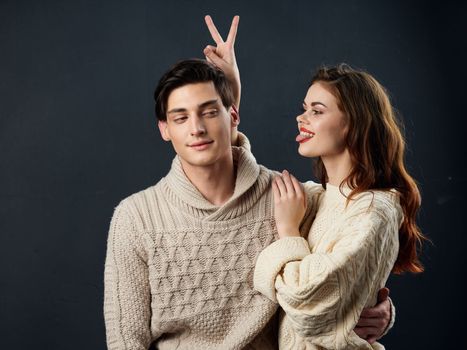 Man and woman in sweater embrace family romance love dark background