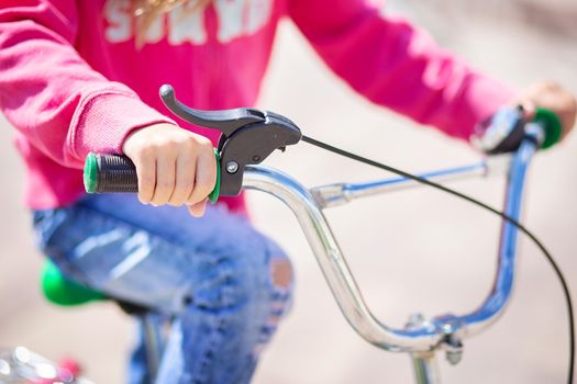 Children's bicycle handlebar with hand brake. The child holds the handlebars of the bike. Healthy lifestyle concept