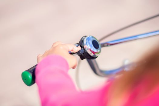 Handlebar of a children's bicycle with a bell. The child presses the bell of the bike. Security