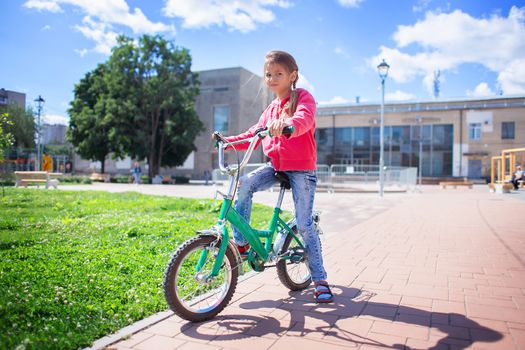 Girl rides a child's bike in a summer park