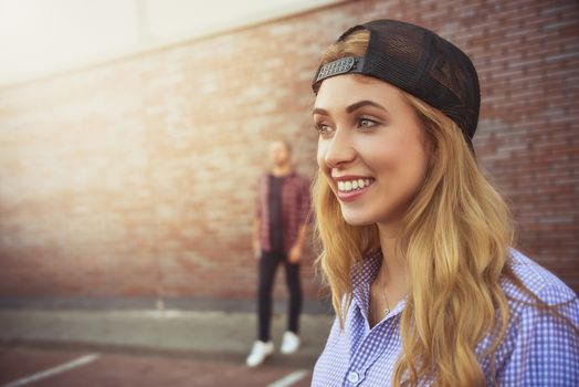 Pleased Caucasian teenage girl wears black cap and shirt, going to have stroll with friends, poses against white background. Youngster woman dressed in fashionable clothes.