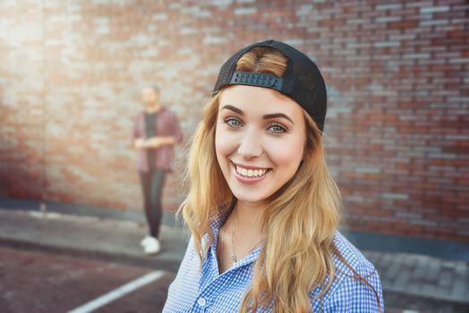 Pleased Caucasian teenage girl wears black cap and shirt, going to have stroll with friends, poses against white background. Youngster woman dressed in fashionable clothes.
