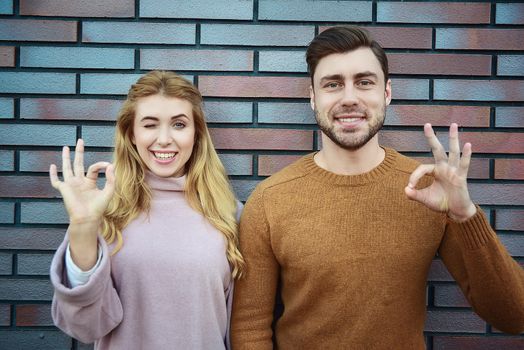 Graceful cheerful positive young woman and man have satisfied expressions, keep both hands on heart, feel thankful to guests, being in high spirit, stand against white background.