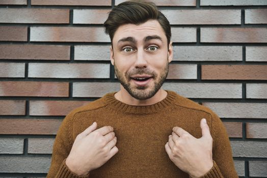 Young adult man over brown brick wall screaming proud and celebrating victory and success very excited, cheering emotion.