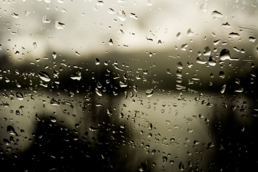 Rain drops on a window with dark background, moody and dark, autumn or winter rain.