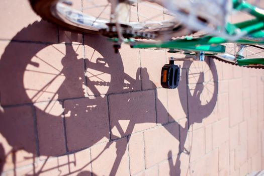 The shadow of a children's bike and spoked wheels on paving stones in the park. Healthy lifestyle