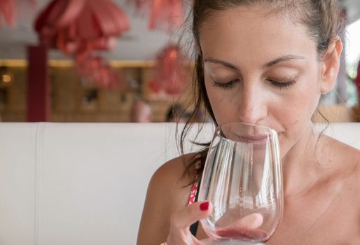 Closeup portrait of young woman with ponytail drinking red wine. Leisure, drinks, degustation, people and holidays concept. Defocused blurry background.