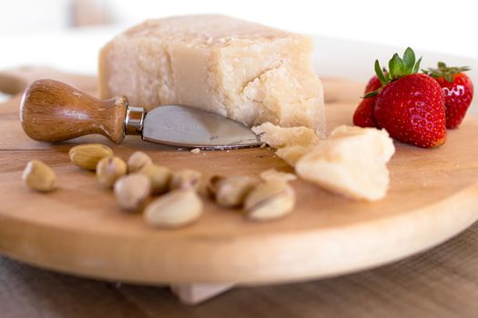Chopping board with cheese, pistachios and strawberries.